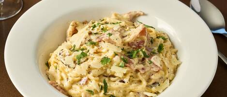 A bowl of creamy pasta with herbs on a table.
