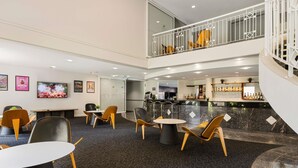 Un'hall d'albergo con una zona salotto, un bar e una scalinata.
