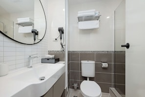 Ein modernes Badezimmer mit Waschbecken, Spiegel und Toilette in Weiß.