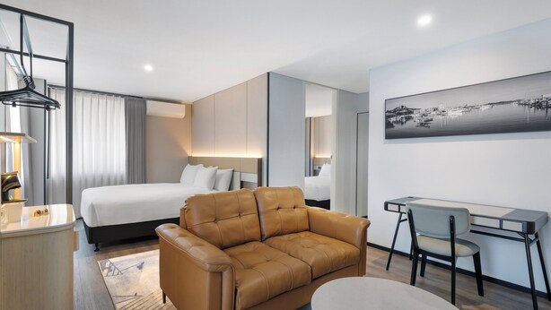 A modern hotel room with a bed, a sofa, a desk, and a chair. - Holiday Inn Townsville by IHG (Townsville)