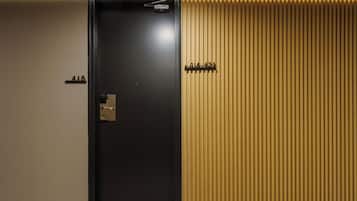 A hotel room with a black door, a beige wall, and a wooden panel wall.