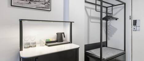 Una habitación moderna con una cama, una mesita de noche con una tetera y un cuadro en la pared.