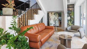 A modern living room with a leather sofa, a round coffee table, and a staircase with a railing. - Holiday Inn Townsville by IHG (Townsville)