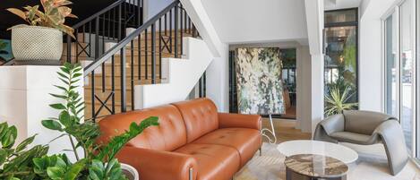 A modern living room with a leather sofa, a round coffee table, and a staircase with a railing.