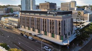 Un edificio moderno con un evidente cartello 'Holiday Inn', caratterizzato da una struttura a più piani con tetto piatto e una serie di balconi.