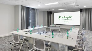 A conference room with a long table, chairs, a projector screen, and water bottles. - Holiday Inn Townsville by IHG (Townsville)
