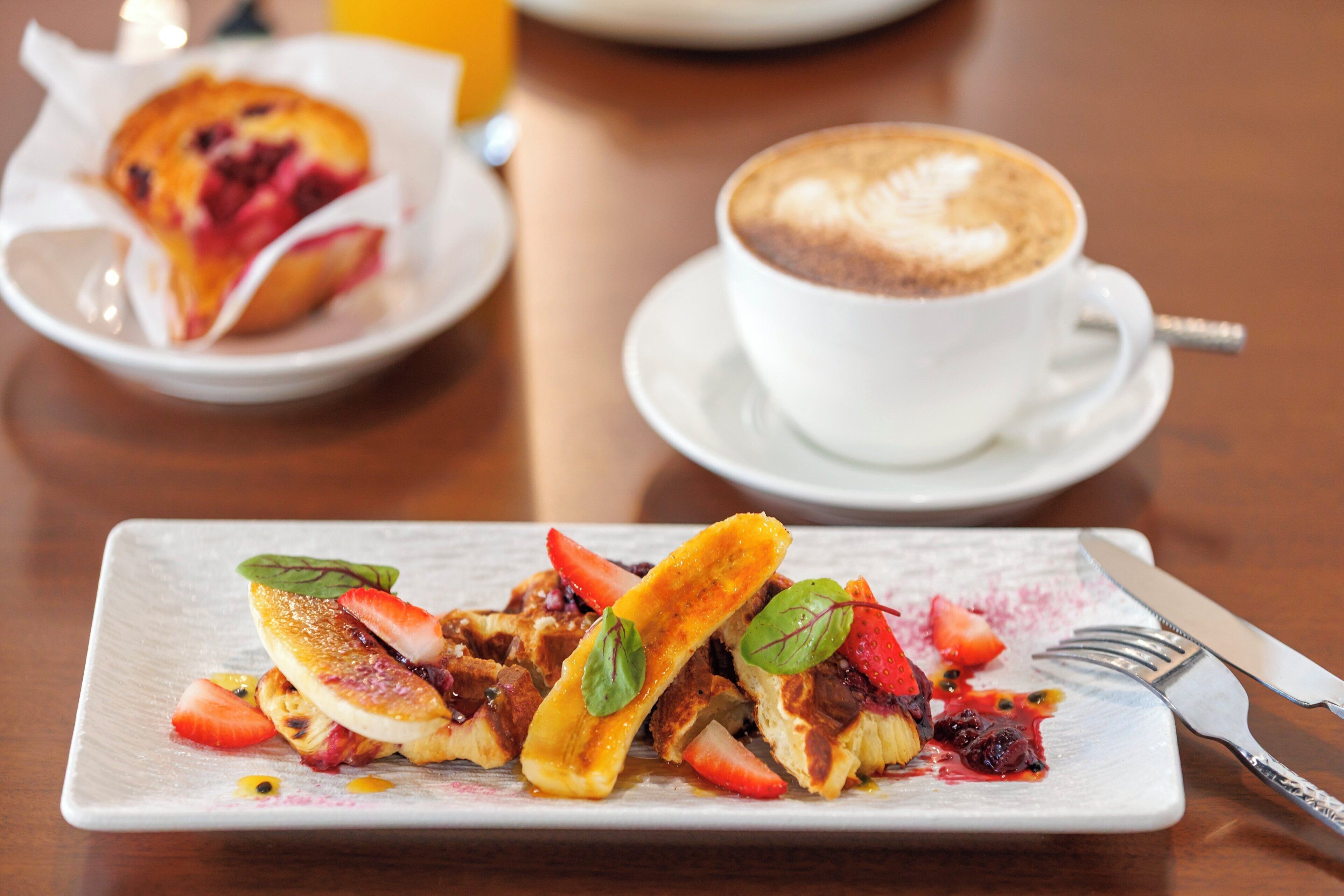 A breakfast setting with pancakes, strawberries, and a cup of coffee on a table.