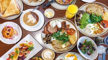 Variedad de platos para el desayuno, incluyendo tostadas, huevos y fruta, sobre una mesa de comedor.