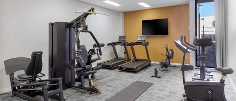 Un gimnasio con cintas de correr, máquinas de pesas y bicicletas estáticas.
