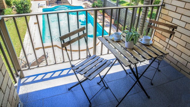 A balcony with a pool, wooden furniture, and a view of the backyard. - Ryde Inn (Ryde)
