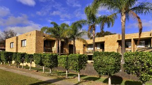 A modern building with brick walls, multiple balconies, and a well-maintained garden with various trees and shrubs. - Ryde Inn (Ryde)