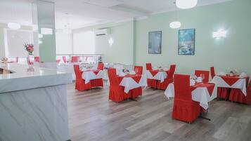 Un restaurante con mostradores de mármol, sillas rojas y manteles blancos.