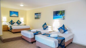 A hotel room with two beds, each with a blue and white bedspread, and matching pillows. There are two bedside tables with lamps, and the walls are decorated with framed pictures of tropical scenes. - Ryde Inn (Ryde)