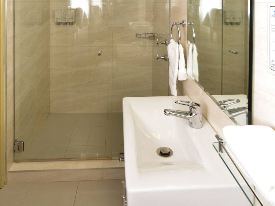 A modern bathroom with a glass-enclosed shower, a white sink, and a large mirror.