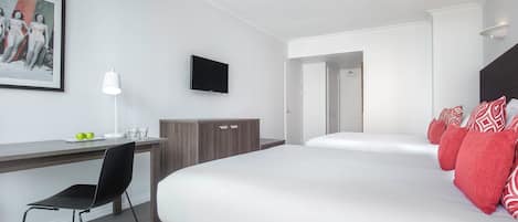Une chambre d’hôtel avec un lit, un bureau et une chaise, une télévision et un tableau encadré au mur.