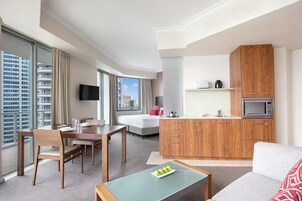 Une chambre d’hôtel moderne dotée d’un coin repas, d’une kitchenette et d’un canapé.