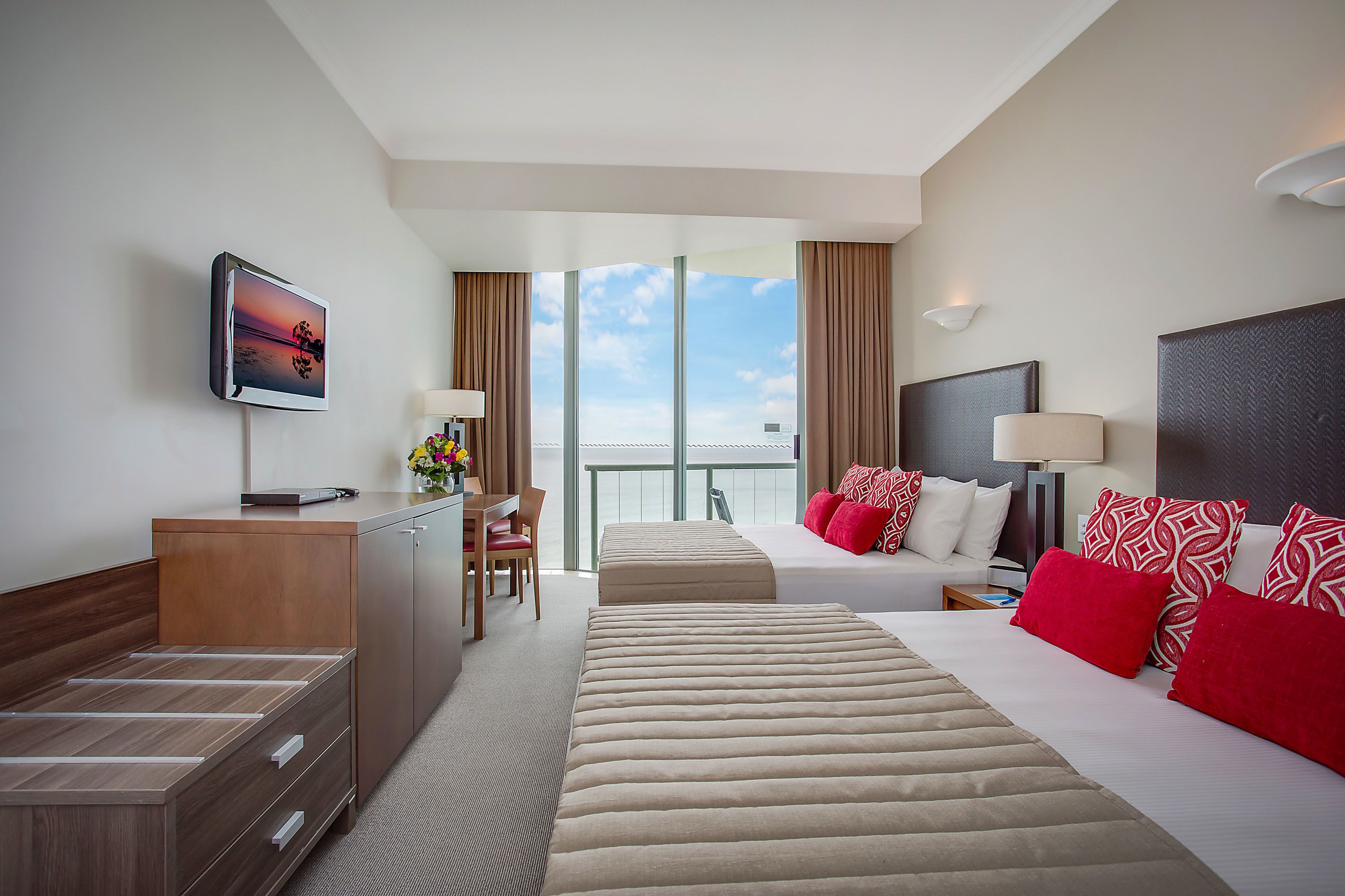 A hotel room with a bed, a desk, a chair, a television, and a large window.