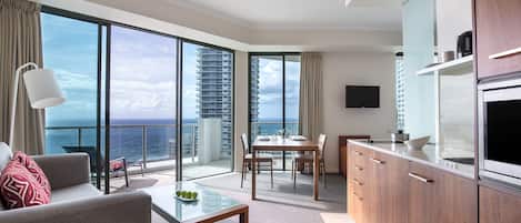 A modern hotel room with a balcony, a dining area, and a kitchen.