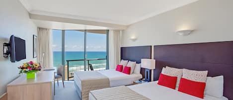 Habitación de hotel con dos camas, un escritorio, una silla y un balcón con vista al océano.