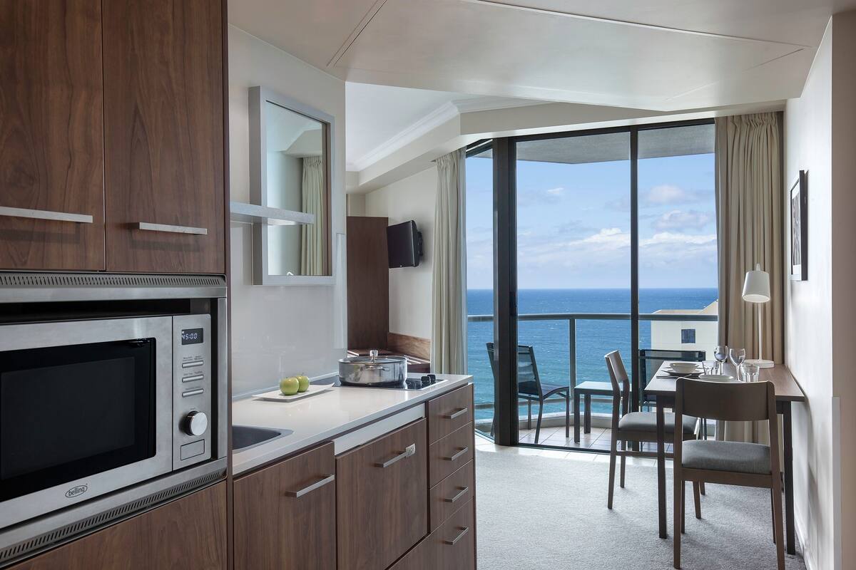 Una cocina moderna con microondas integrado, un comedor con mesa y sillas, y un balcón con vistas al mar.