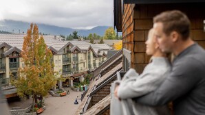 A view of a building with multiple balconies overlooking a courtyard with trees and a mountain in the background. - Executive - The Inn at Whistler Village (Whistler)