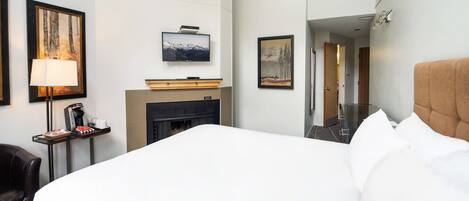 Habitación de hotel con cama, chimenea, televisor y cuadros en la pared.