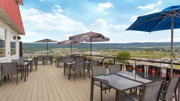 Une terrasse avec coin salon extérieur, comprenant des tables, des chaises et des parasols pour créer de l’ombre.