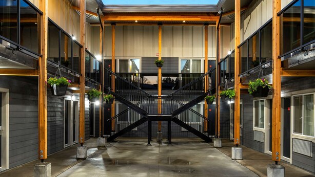 A modern building with a central staircase, wooden beams, and hanging planters. - Econo Lodge (Prince George)