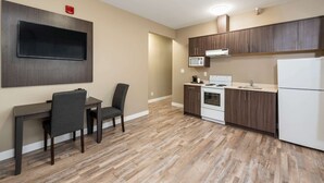 A modern kitchen with wooden cabinets, a microwave, and a refrigerator. - Econo Lodge (Prince George)