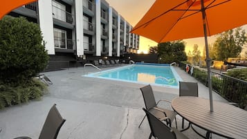 Een buitenzwembad, parasols bij het zwembad en ligstoelen