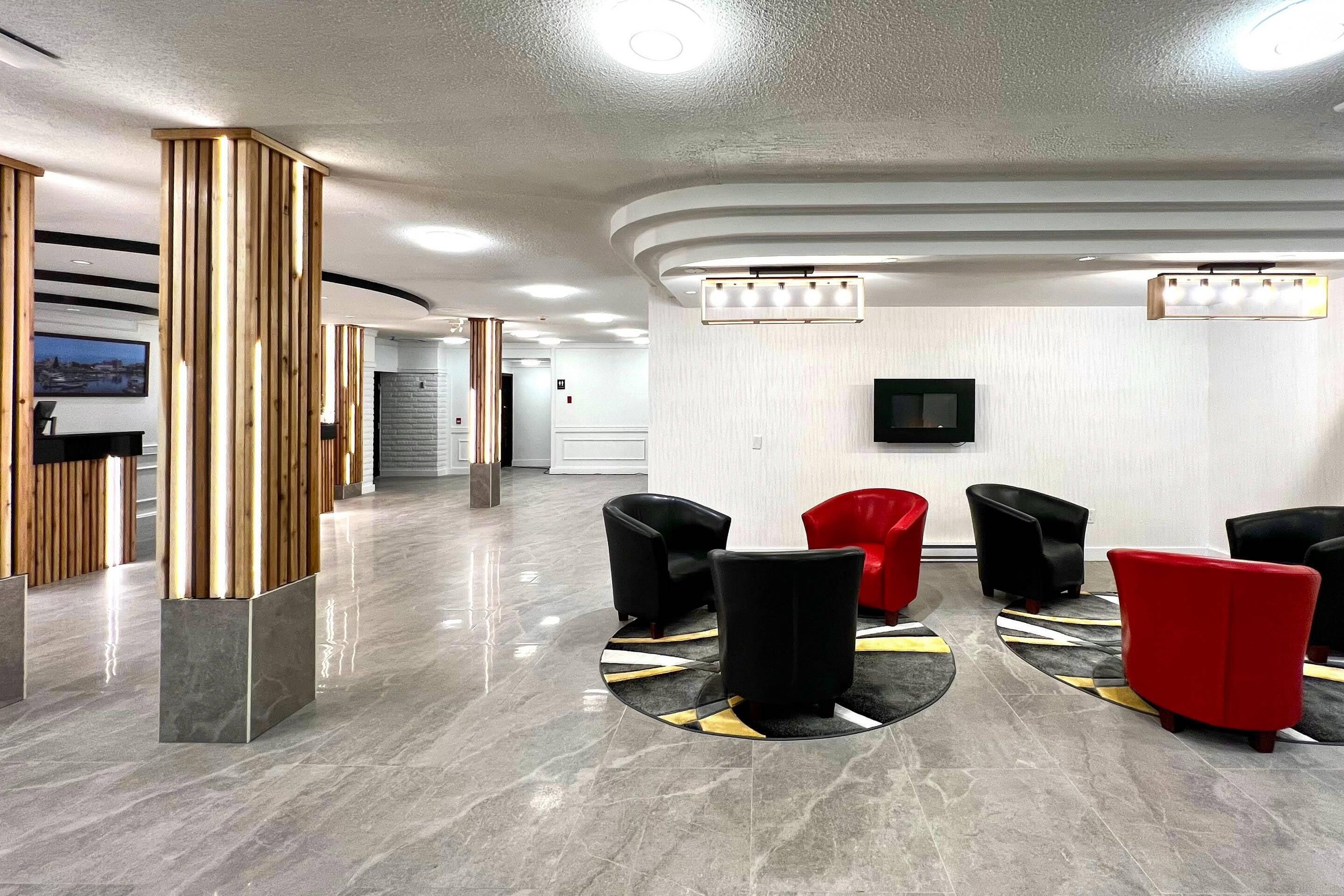 A hotel lobby with a reception desk, seating area, and a television on the wall.