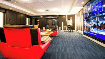 A conference room with a red chair, a table, and a TV screen displaying a sports channel.