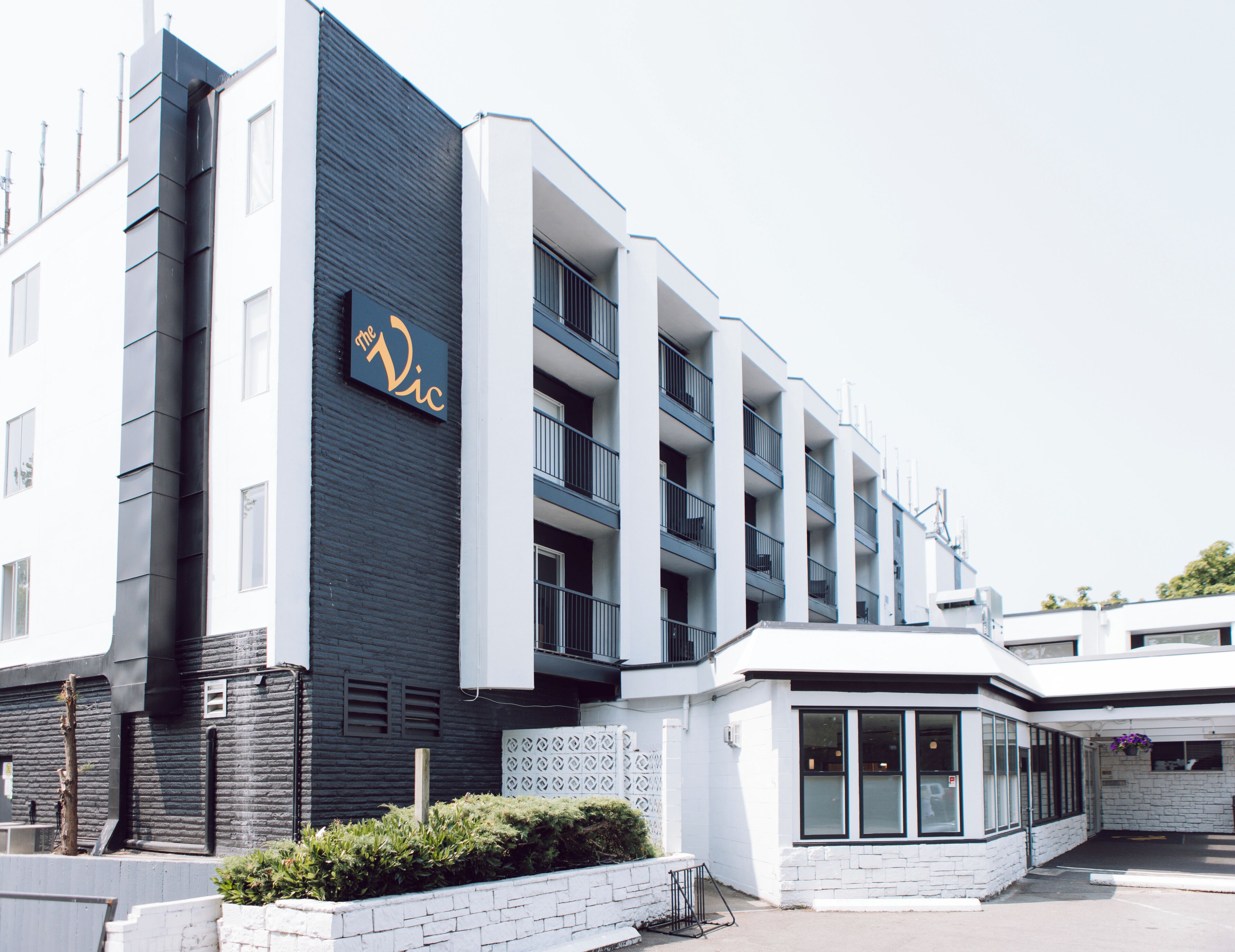 A modern building with a sign reading 'The Vic.' It features multiple floors, balconies, and a white facade.