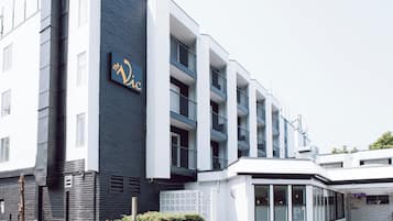 Un edificio moderno con un letrero que dice 'The Vic'. Cuenta con varios pisos, balcones y fachada blanca.