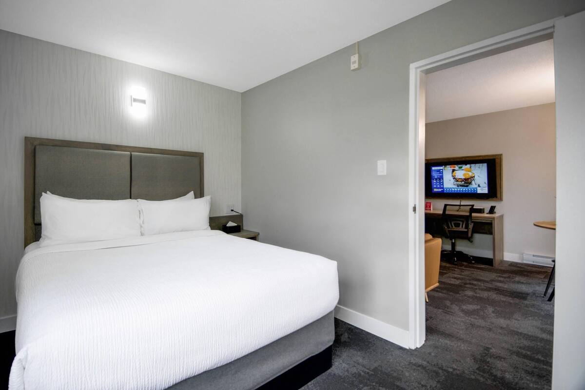 A hotel room with a large bed, a desk with a computer, and a television.