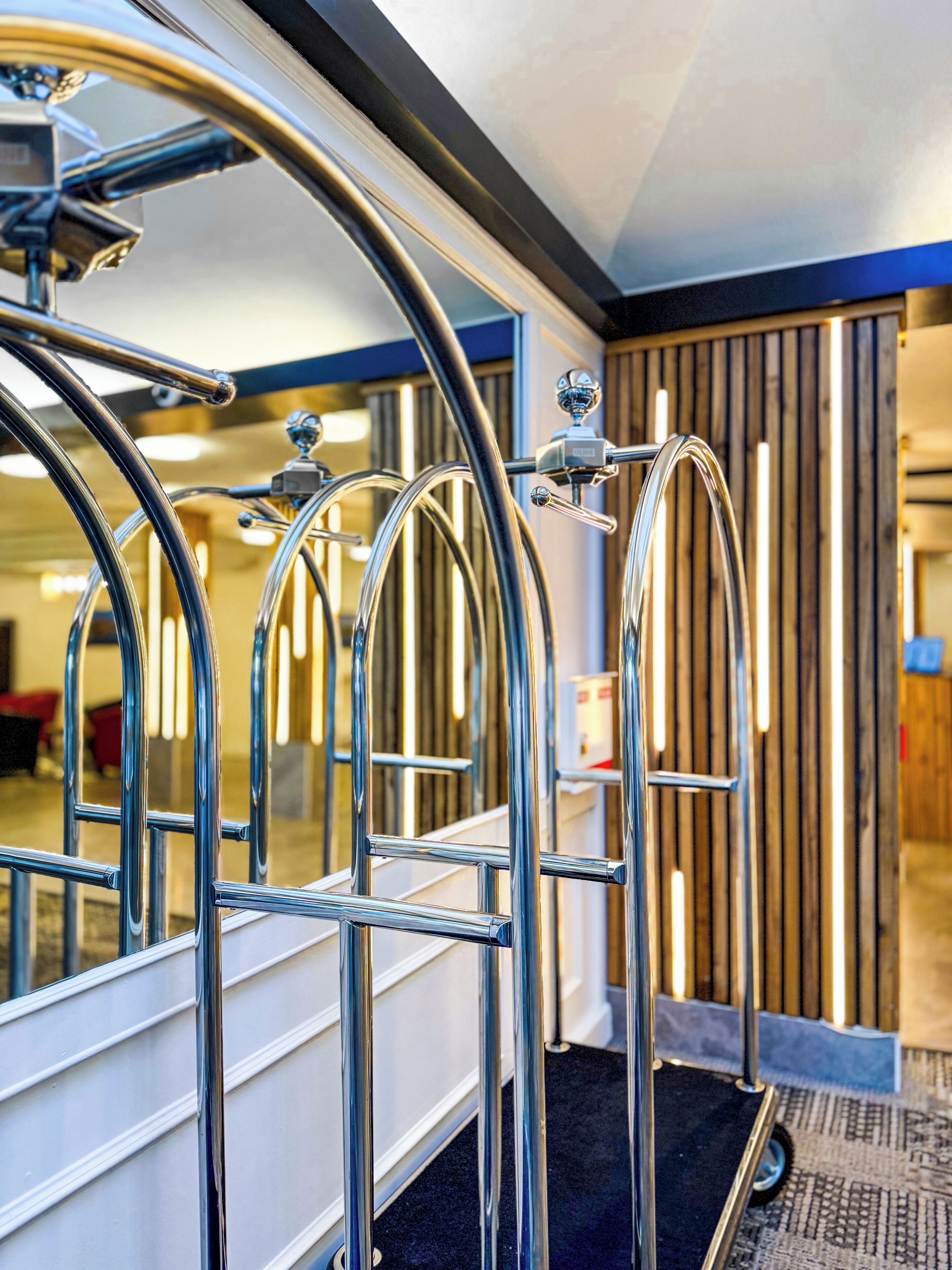 Ein Hotelinneres mit Metallgeländern, einer Rezeption und einer Wandpaneelausstattung aus Holz.