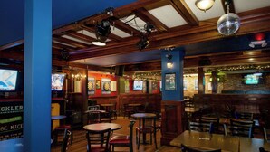 A bar with wooden furniture, multiple televisions, and a brick wall. - The Vic, an Ascend Collection Hotel (Victoria)