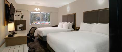 A hotel room with two beds, a desk, a chair, a TV, and a window with a view of buildings.