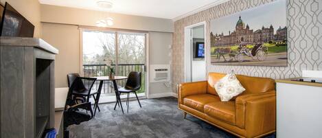 A room with a sofa, chairs, a desk, a television, and a large window.
