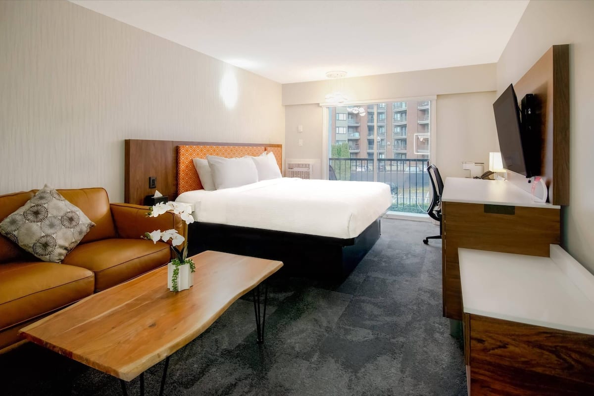 A hotel room with a bed, a sofa, a desk, and a TV.