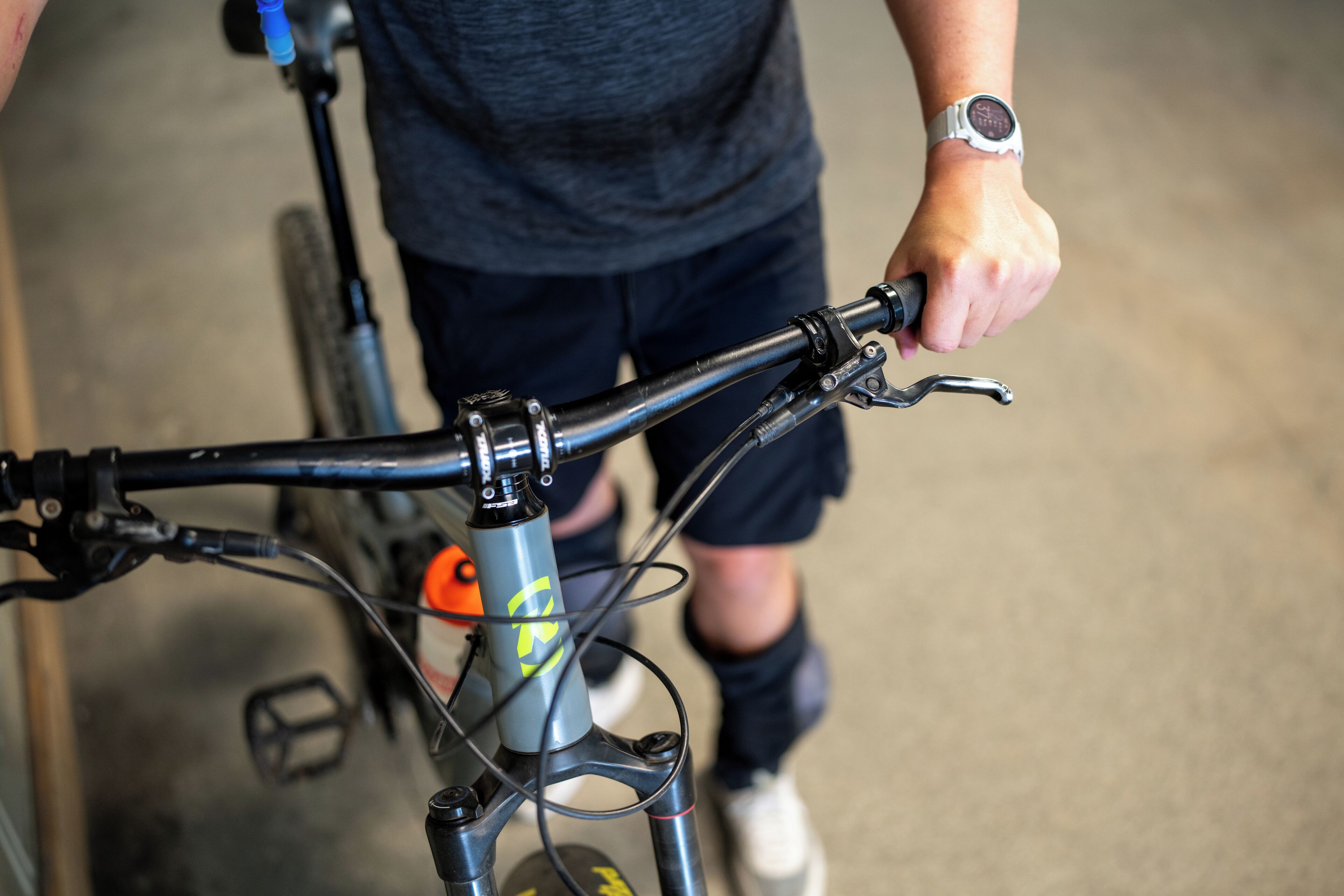 Ein Detailaufnahme von einem Fahrradlenker mit daran befestigter Trinkflasche.