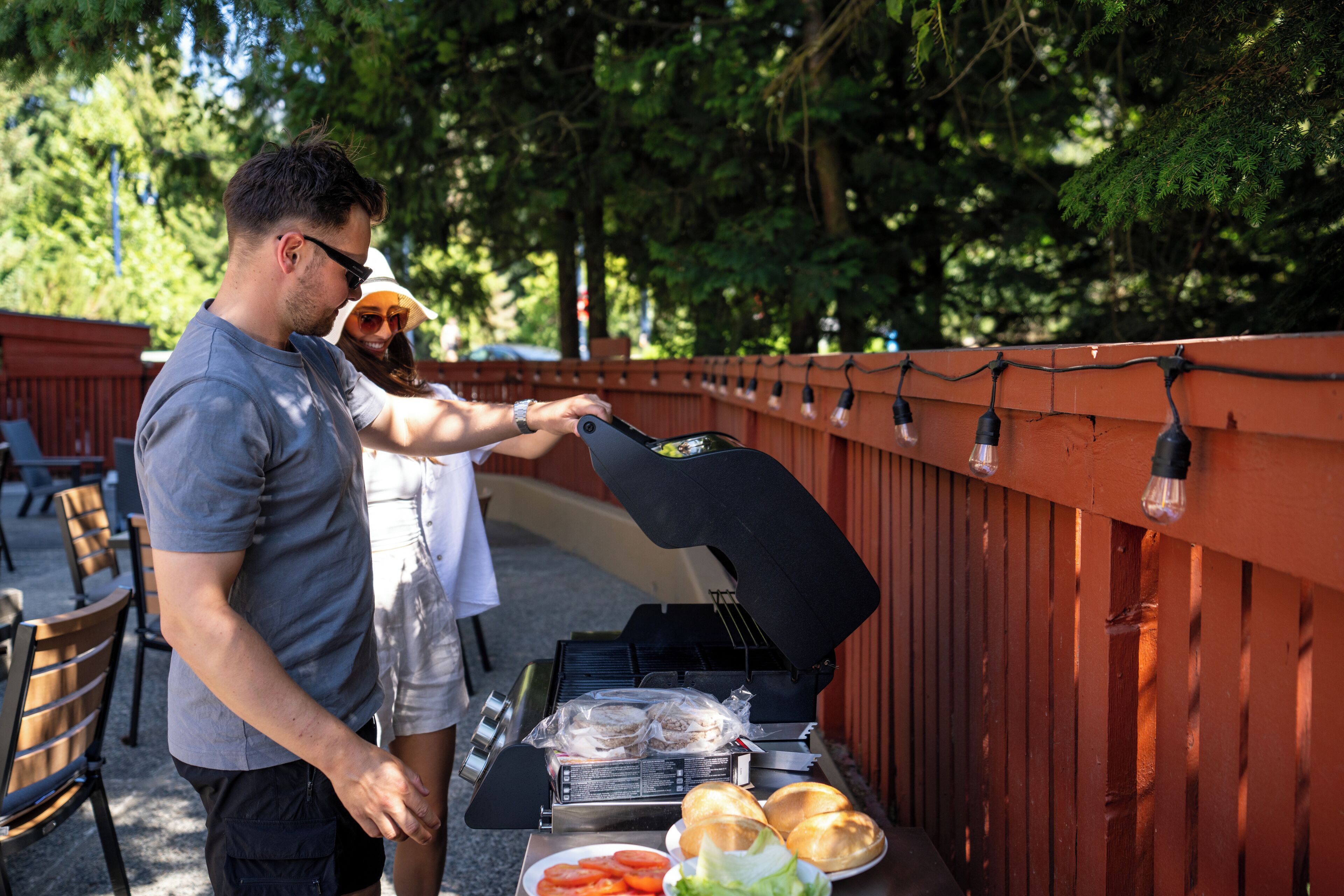 A barbecue grill with food items and a person grilling.