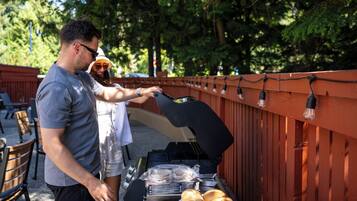 A barbecue grill with food items and a person grilling.