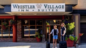 The exterior of Whistler Village Inn & Suites with a brick facade, large windows, and potted plants. - Whistler Village Inn And Suites (Whistler)