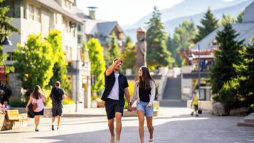 Una pareja caminando de la mano por una calle adoquinada con edificios y árboles al fondo.