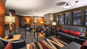 A modern lobby with a stone fireplace, seating areas, and large windows with blinds. - Whistler Village Inn And Suites (Whistler)