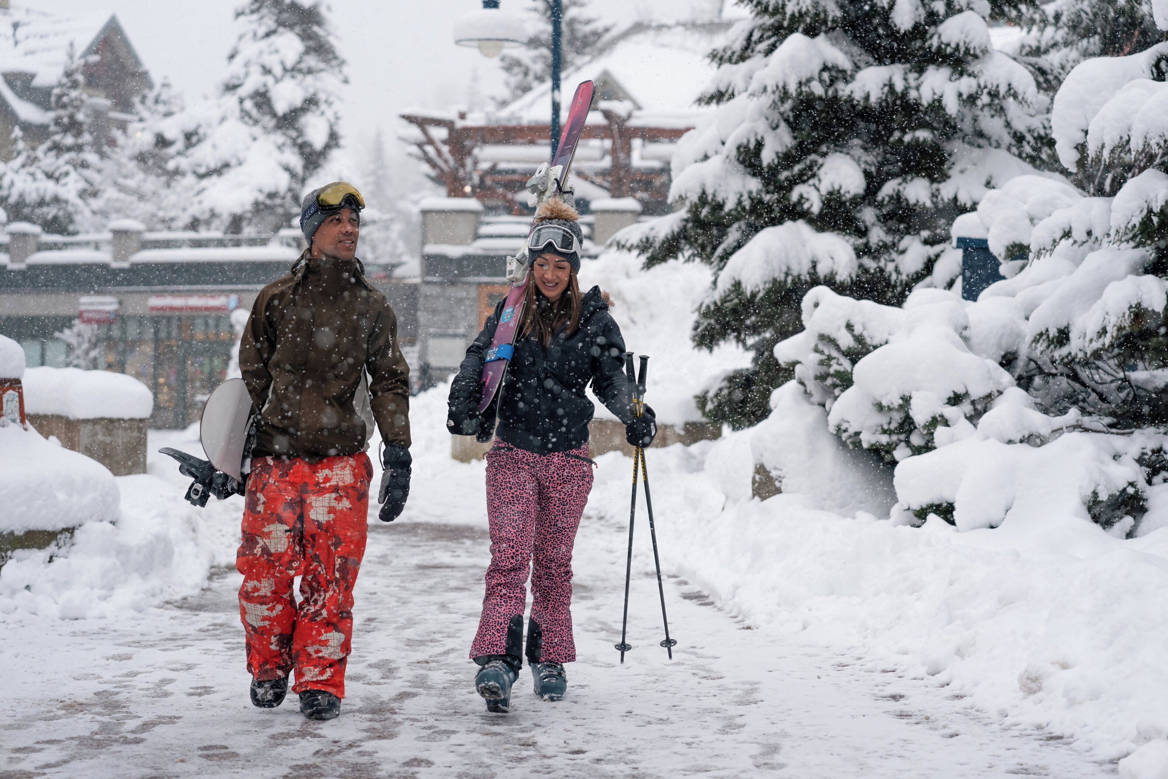 Un sentier enneigé sur lequel marchent deux personnes, l’une portant des skis et l’autre tenant des bâtons de ski.