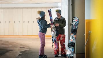 Une personne tenant une planche de snowboard dans un couloir où se trouvent des casiers.