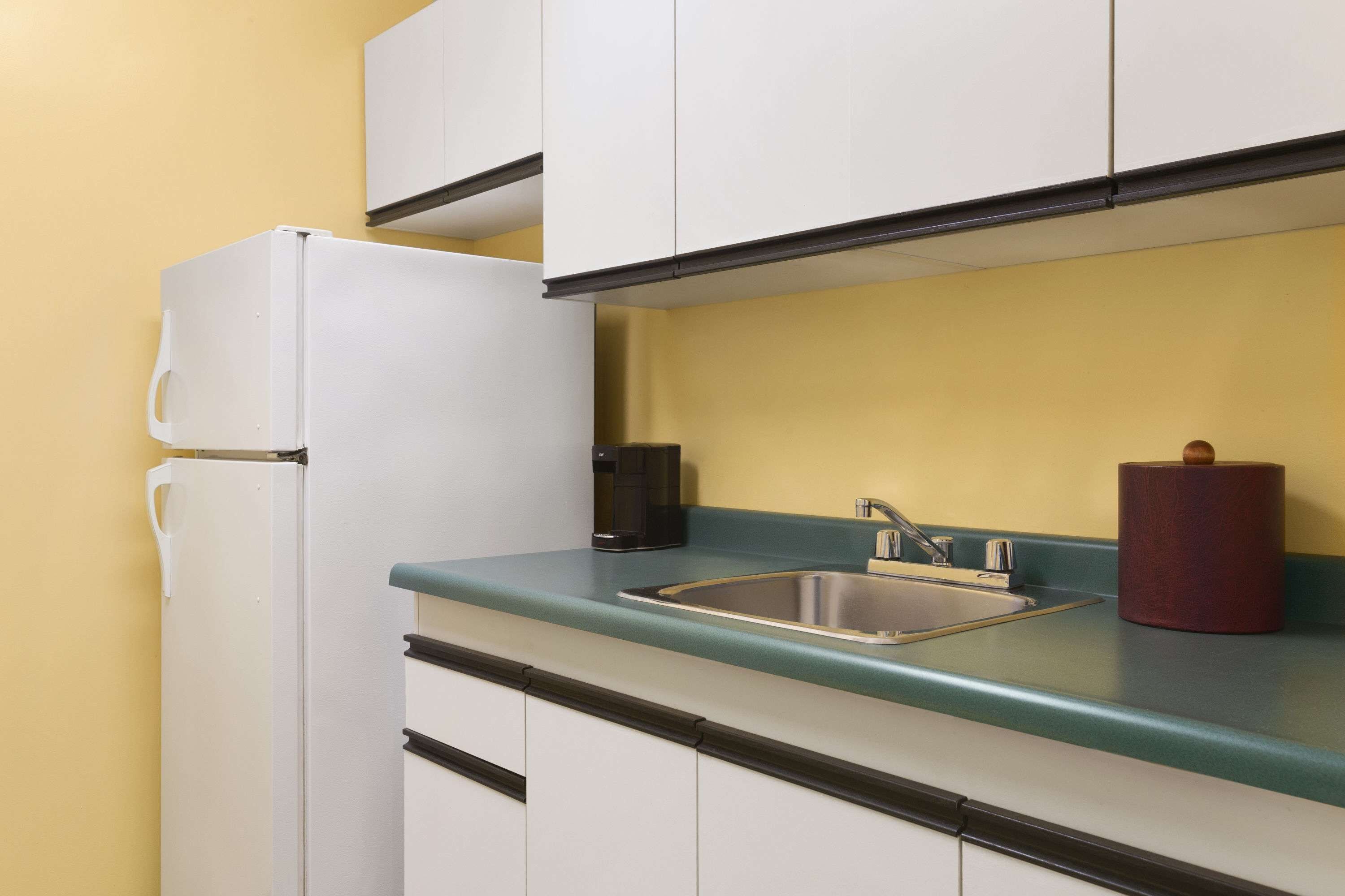 A compact kitchen with a white refrigerator, a sink, and a coffee maker.