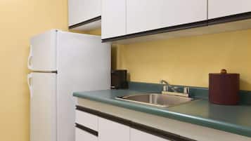 A compact kitchen with a white refrigerator, a sink, and a coffee maker.